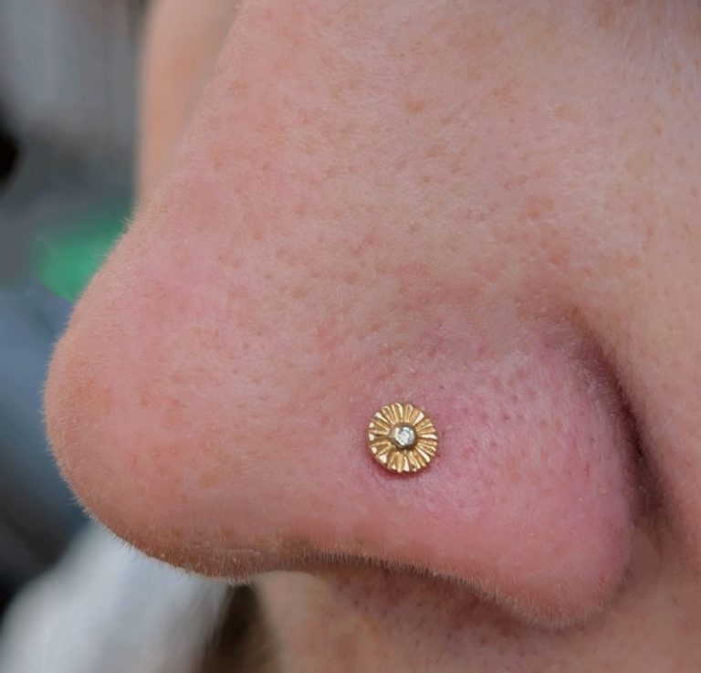 gold stud in nose piercing nose piercing featuring a small gold flower stud by local natives.